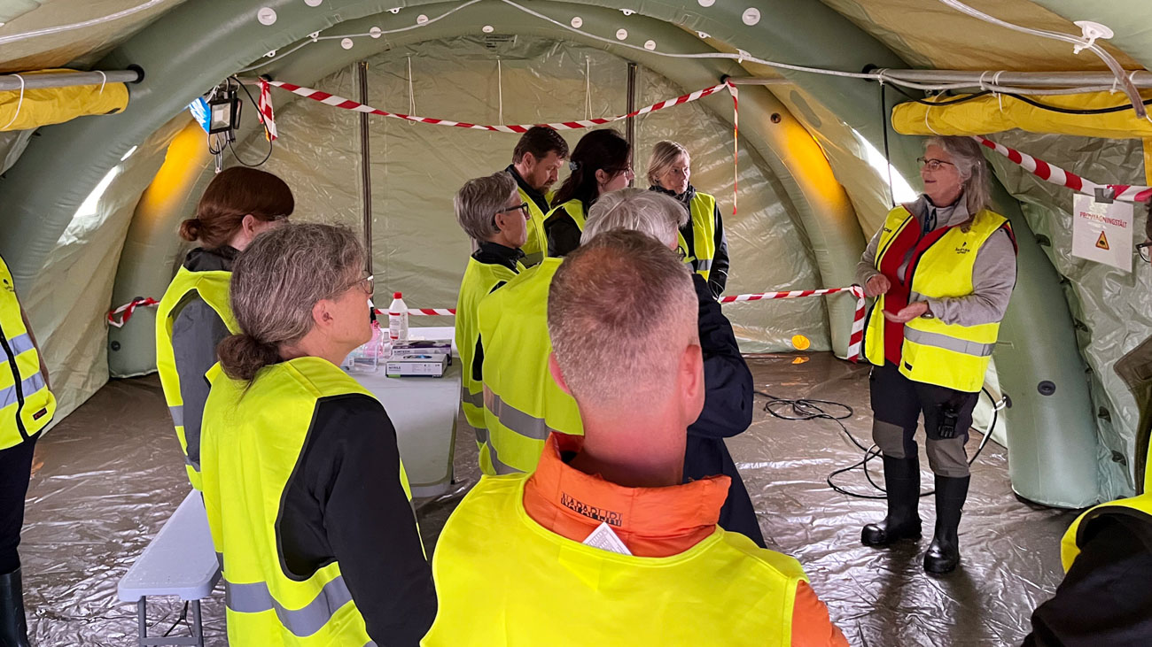 People with high-visibility vests in emergency tents.